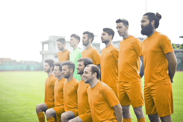 Fußballteam FV Sulzbach in orangefarbenen Trikots, ein Torwartspieler in Neongrün, beim Mannschaftsfoto auf Rasen