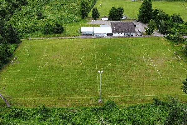Luftaufnahme des Fußballplatzes mit Vereinsheim FV Sulzbach, umgeben von grüner Vegetation und Bäumen